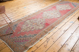 Distressed blush, faded red, and beige geometric pattern of vintage Oushak runner.