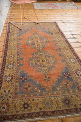 Distressed Oushak rug detail, showing stepped geometric medallion, pale terra cotta, and saffron border.
