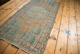 Distressed texture of a vintage Turkish Oushak runner, highlighting faded peach and mint green patterns.