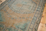 Vintage Oushak rug's worn pile, revealing pearl motifs and faded peach, green tones.