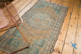 Distressed corner of vintage Oushak runner with pearl motif and faded green tones.