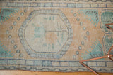 Texture detail of distressed Oushak runner, showing worn peach field and faded green border.