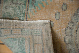 Vintage distressed Oushak rug pile with peach and mint green tones, showing woven foundation.
