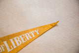 Pointed end of a vintage yellow felt pennant with white 'LIBERTY' lettering.