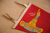 Vintage red felt Statue of Liberty pennant showing white binding and frayed ties.
