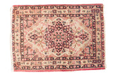 Antique Kerman rug with a scalloped starburst medallion in navy and cochineal red on an ivory field.