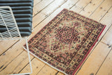Lifestyle view of a small antique Kerman rug showcasing its red and navy starburst medallion design.
