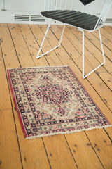 A small antique Kerman rug mat shown in a room to demonstrate its scale and traditional style.