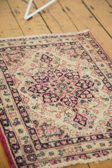 Angled view of an antique Kerman rug's scalloped medallion in raspberry red and navy blue.