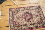 Antique Kerman rug mat with a floral medallion shown in a naturally lit room setting.