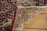 Flipped corner of an antique Kerman rug showing its hand-knotted weave and finished edge.