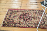 Lifestyle view of a small antique Kerman rug with a central starburst medallion.
