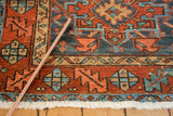 Hand-knotted texture of Karaja rug's madder red and denim blue serrated leaf border, white fringe.
