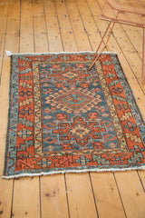 Vintage Karaja rug corner featuring geometric patterns, denim blue, madder red, and white fringe.