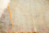 Distressed vintage Oushak rug texture showing faded beige, blue, and bright pink elements.