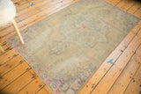 Distressed Oushak rug corner featuring rococo arabesques in hot pink, beige, and silver.