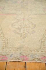 Distressed pile texture of a vintage Oushak rug, dusty beige field, bright pink details.