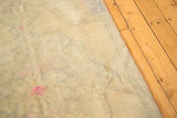 Vintage distressed Oushak rug with dusty beige field and prominent bright hot pink staining.