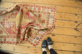 Vintage Oushak rug folds, showing distressed dusty red and saffron yellow floral patterns.