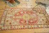 Vintage distressed Oushak rug corner with faded floral border and stepped spandrel.
