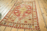 Faded cherry red, saffron yellow, and ivory floral borders on distressed vintage Oushak rug corner.