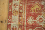 Distressed red and saffron yellow Oushak rug edge showcasing diminutive floral motifs.