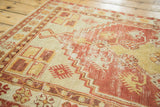 Distressed vintage Oushak rug with dusty red, saffron, ivory stepped motifs.