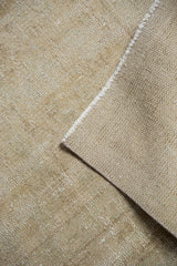 Folded distressed Oushak carpet with worn textured pile in pale beige and ivory.
