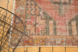 Worn vintage Oushak rug corner, serrated geometric patterns in soft red, charcoal, ivory.