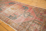Distressed red, orange, charcoal pile with serrated geometric medallion and border.