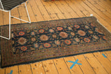 Corner of antique Persian Lilihan rug runner, with indigo arabesque pattern and tattered fringe.
