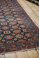 Angled perspective on the repeating veramin motif and intricate borders of a vintage Malayer rug.