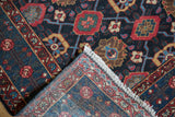 Corner of a vintage Malayer rug folded back showing the fine hand-knotted foundation.
