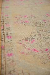 Textured pile of a distressed Oushak runner, highlighting beige, silver, and bright pink floral motifs.