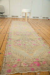 Bright pink floral motifs and worn texture on a distressed Oushak runner.