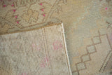 The hand-knotted back and textured, distressed pile of the beige Oushak runner with pink dots.