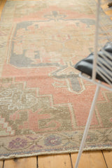 Vintage Oushak rug's distressed surface, dusty rose, faded blue, and beige geometric pattern.