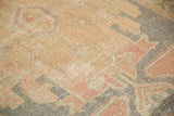 Distressed Oushak rug texture showing even wear, faded rose, beige, and muted blue geometry.