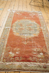 Distressed Oushak rug end with time-softened cinnabar red, ivory, and ornate rococo border.