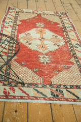 Distressed cherry red field with antique ivory lattice corner patterns of a vintage Oushak rug.