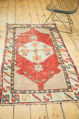 Distressed vintage Oushak rug corner with cherry red field, lattice ivory spandrel, and geometric border.