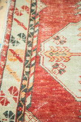 Worn cherry red Oushak pile with geometric ivory and tangerine patterns.