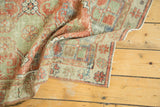 Corner of vintage distressed Oushak rug, showing even wear to knot heads and faded red, green, ivory borders.