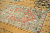 Distressed Oushak rug section: faded brick red, sea foam green floral motifs, stepped border.