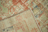 Distressed Oushak rug detail showing textured pile, hand-knotted foundation, with faded red and green tones.