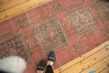 Distressed vintage Oushak runner, dusty raspberry field with faded rectilinear gul and floral motifs.
