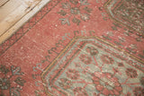 Distressed Oushak rug corner featuring raspberry, pale blue, charcoal Kufic and floral motifs.