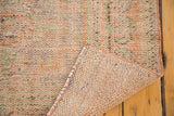 Distressed Oushak runner's textured pile and hand knotted foundation with secured edge.