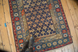 Caucasian rug's blossomed flower motif on a camel field with dark navy and brick red accents.