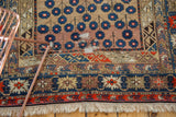 Antique Caucasian rug's geometric borders, unidirectional blossom motif, and professionally restrung foundation.